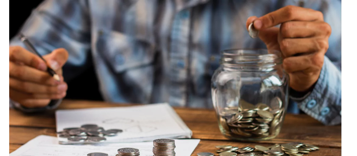 person putting coins in a jar